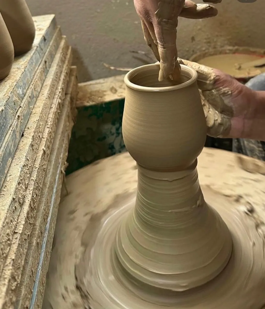 A craftsperson shaping a stoneware cup on a pottery wheel in Nepal